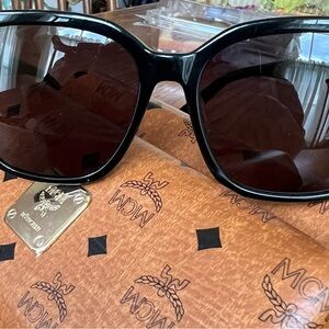 MCM Black Sunglasses. Unisex frames embellished with the signature logo on side.